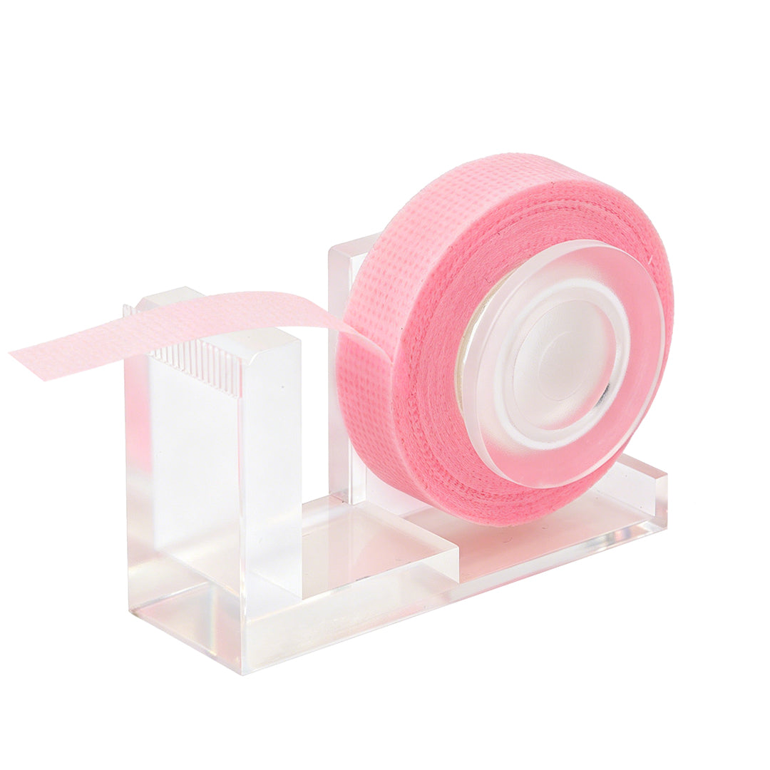 Clear acrylic lash tape dispenser with a pink tape roll and a built-in cutting edge, shown on a white background.