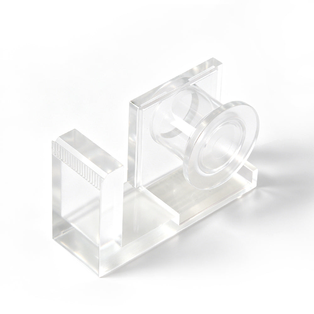 Clear acrylic lash tape dispenser with a pink tape roll and a built-in cutting edge, shown on a white background.