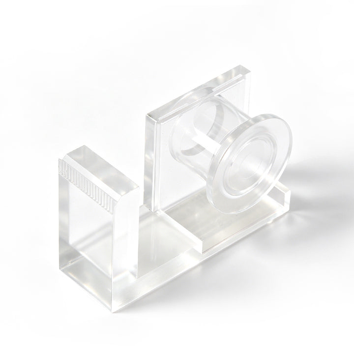 Clear acrylic lash tape dispenser with a pink tape roll and a built-in cutting edge, shown on a white background.