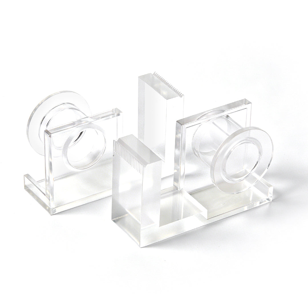 Clear acrylic lash tape dispenser with a pink tape roll and a built-in cutting edge, shown on a white background.