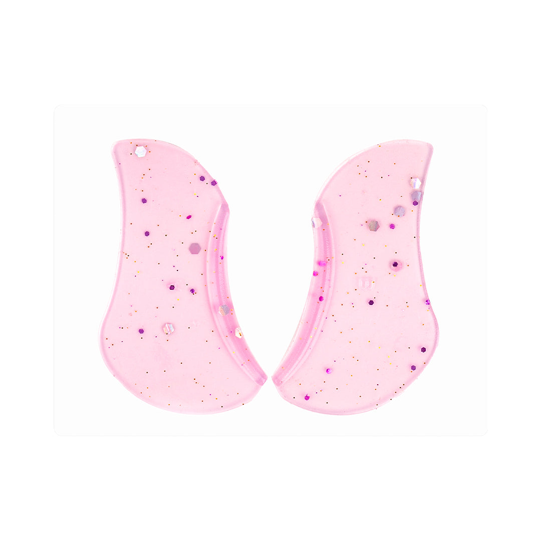 Two pink glitter underlash lift shields with curved anatomical edges, made from soft silicone for professional lower lash treatments.