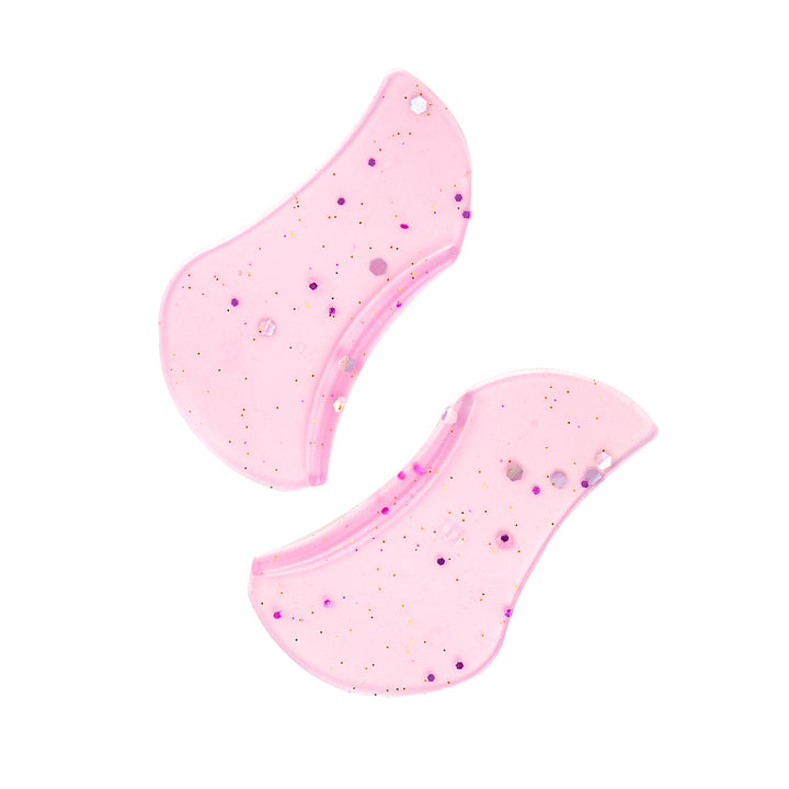 Two pink glitter underlash lift shields with curved anatomical edges, made from soft silicone for professional lower lash treatments.